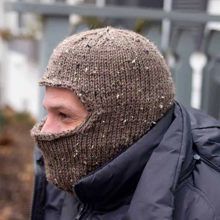 a man wearing a knitted hat and jacket looking off to the side with his face covered in dirt