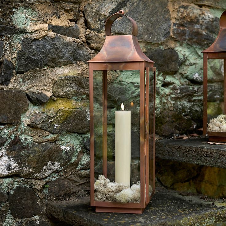 two brown lanterns sitting on top of a stone step next to a wall with moss growing in them