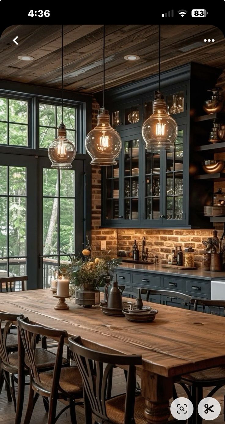 a wooden table surrounded by chairs in a kitchen next to a large window with lots of windows