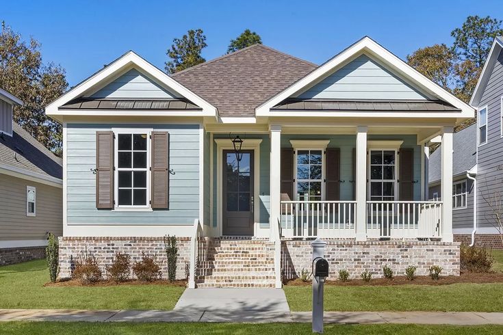 a blue house with white trim and two windows on the front porch, surrounded by grass