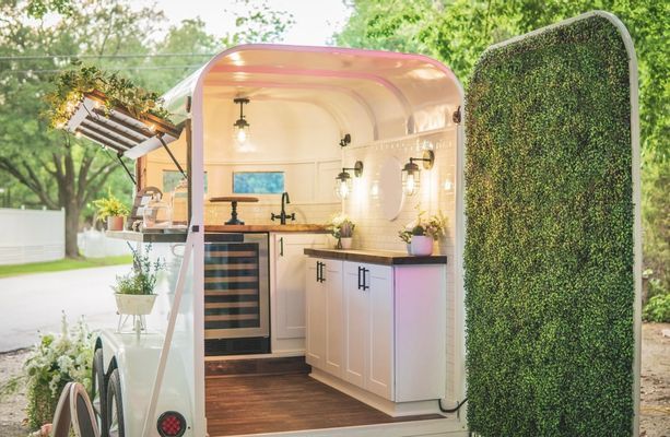 a tiny kitchen is built into the side of a trailer with plants growing on it