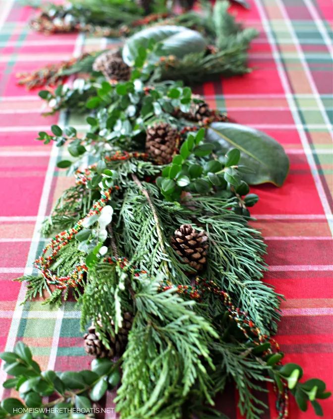 christmas garland with pine cones and greenery on a red plaid tableclothed table