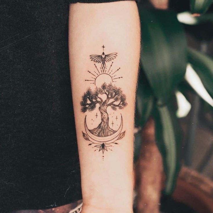 a woman's arm with a tree and moon tattoo on the left inner forearm