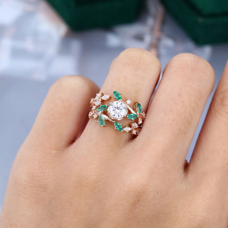 a close up of a person's hand wearing a ring with an emerald and diamond