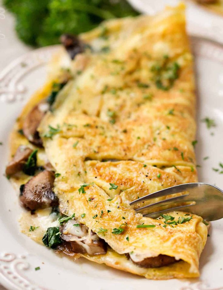 an omelet on a white plate with a fork in it and parsley