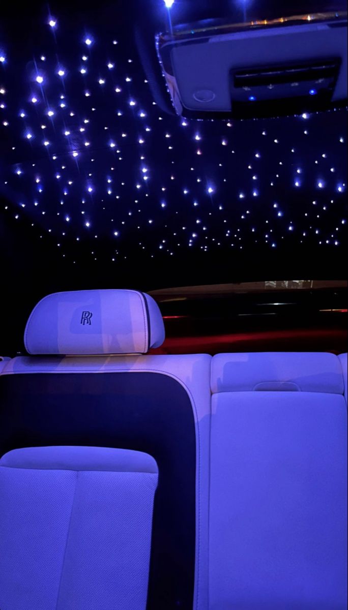 the interior of a car with blue lights shining on the ceiling and white leather seats