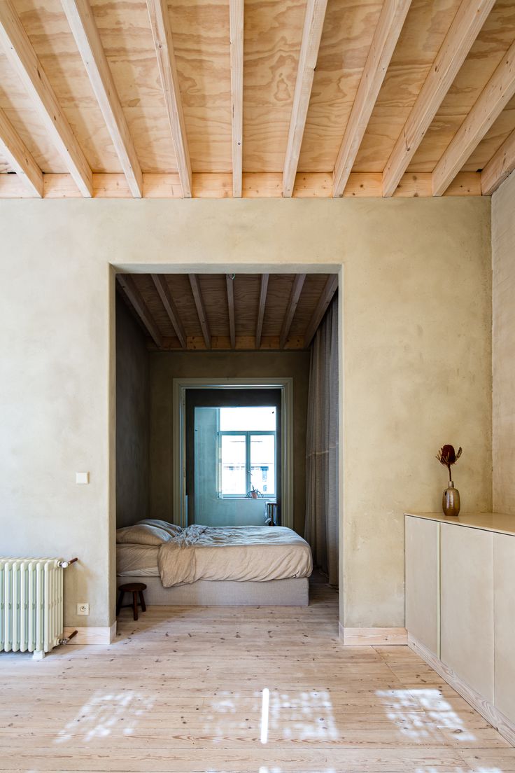 an empty room with a bed, radiator and window in the middle is shown