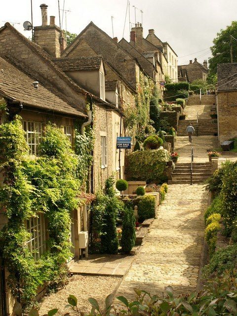 a cobblestone street lined with stone houses and ivy growing on the buildings along it