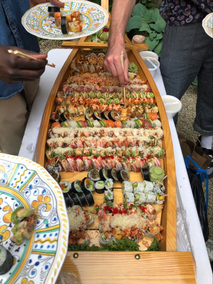 a long boat filled with sushi on top of a table next to other plates