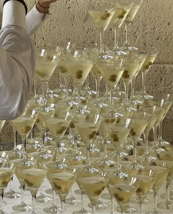 a man standing in front of a bunch of glasses filled with wine and martinis