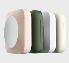 four different colored speakers are lined up in the same row and one is white, green, pink, blue