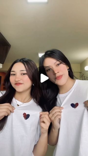 two young women standing next to each other in front of a mirror with hearts on their t - shirts