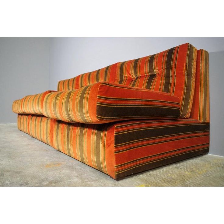 an orange and brown striped couch sitting on top of a floor