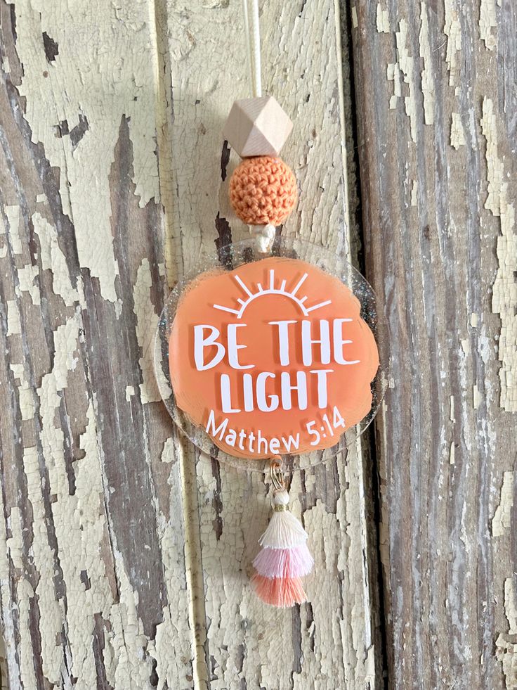 an orange sign hanging from the side of a wooden door with tassels on it