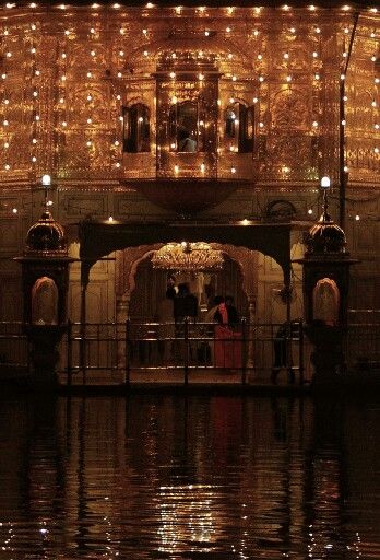 people are standing on the dock in front of a building with lights all over it