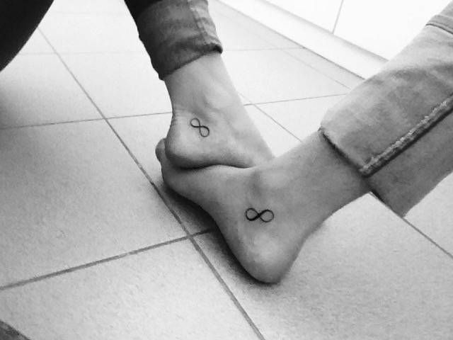 two people sitting on the floor with their feet crossed and one is wearing a bow tattoo