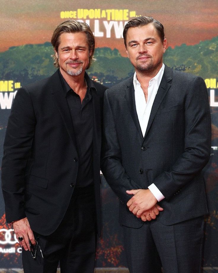 two men standing next to each other on a red carpet