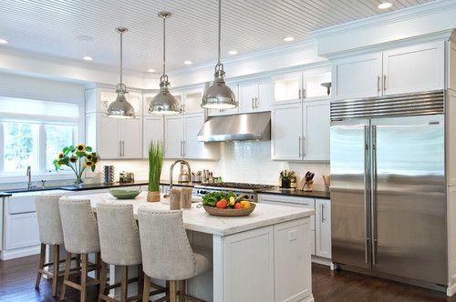 a kitchen filled with lots of white furniture and counter top space next to a refrigerator