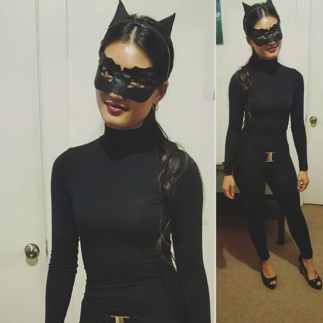 a woman wearing a cat mask and black catsuit is standing in front of a door