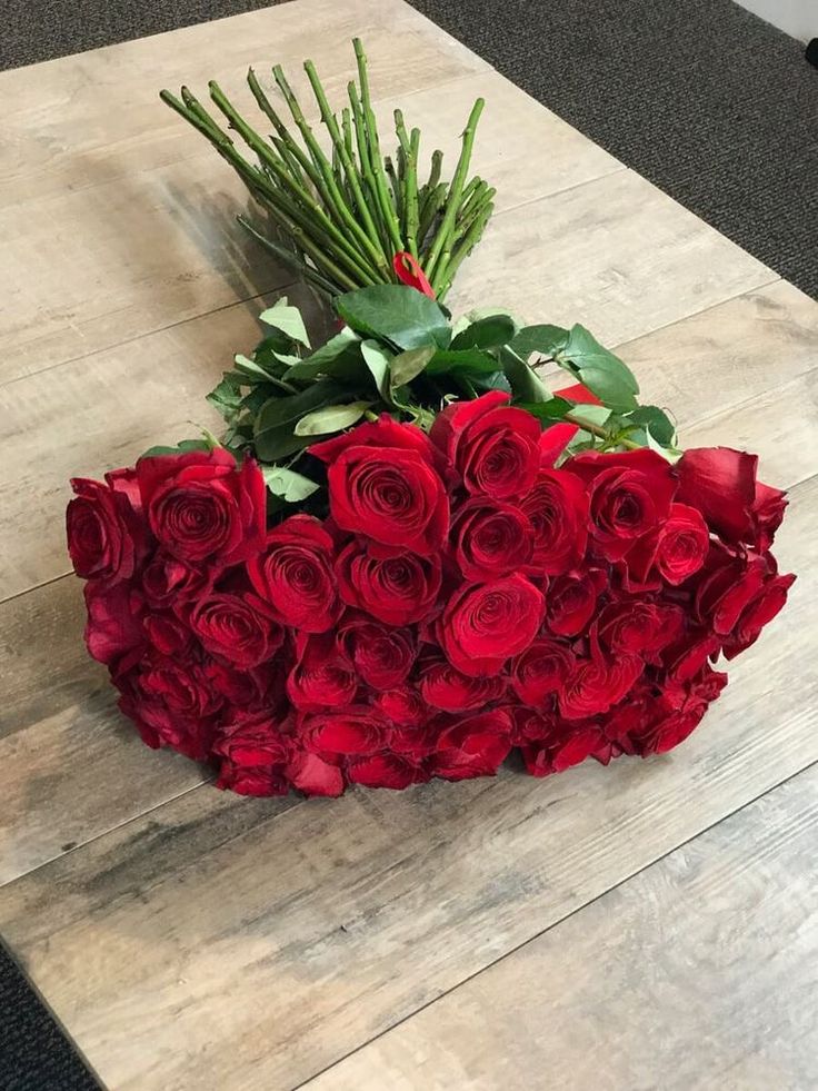 a bouquet of red roses sitting on top of a wooden table