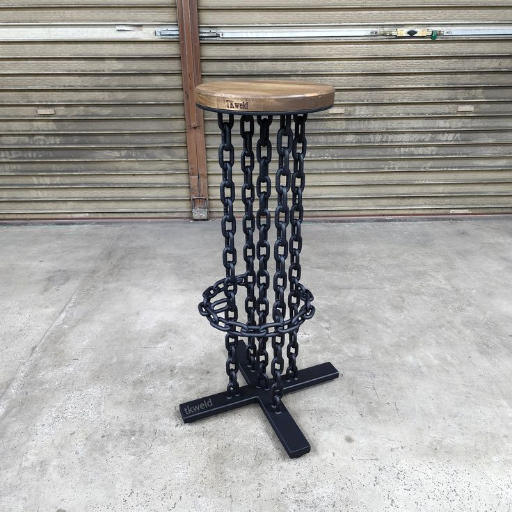 a table made out of chains sitting on top of a cement floor next to a garage door