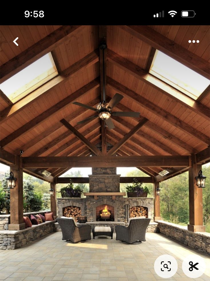 an outdoor living area with fireplace and ceiling fan