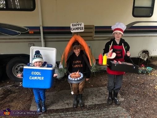 three children in funny costumes holding up coolers and hotdogs on the road