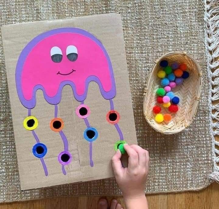 a child's hand is drawing on a piece of paper with jellyfish shapes