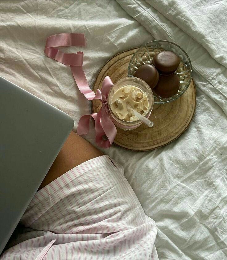 a woman laying in bed with her laptop and some chocolates on top of it