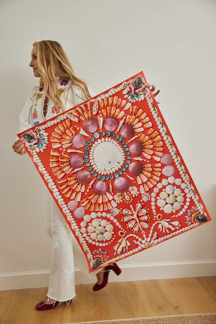 a woman holding an orange and red piece of art