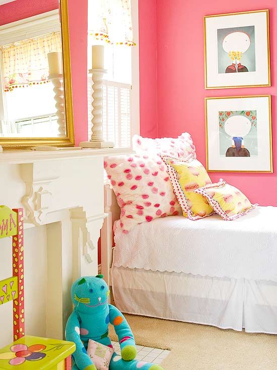 a bedroom with pink walls, white bedding and colorful accessories on the floor in front of a fireplace