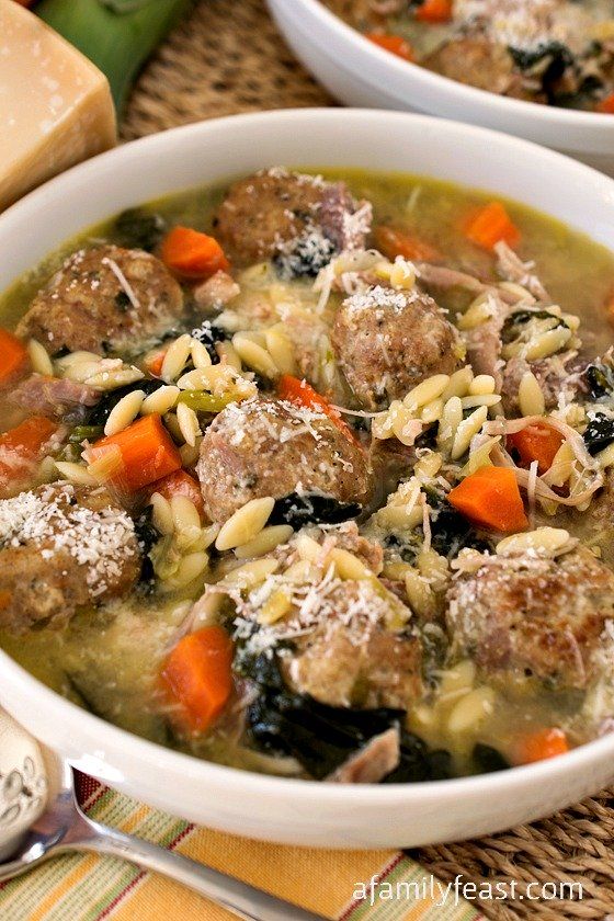 two white bowls filled with meatball soup on top of a woven place mat next to bread