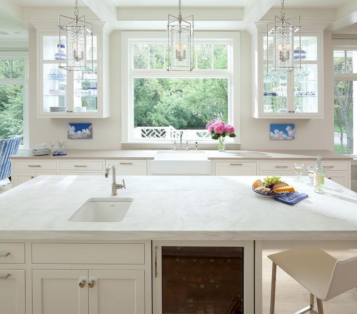 a large kitchen with white cabinets and marble counter tops, an island in the middle