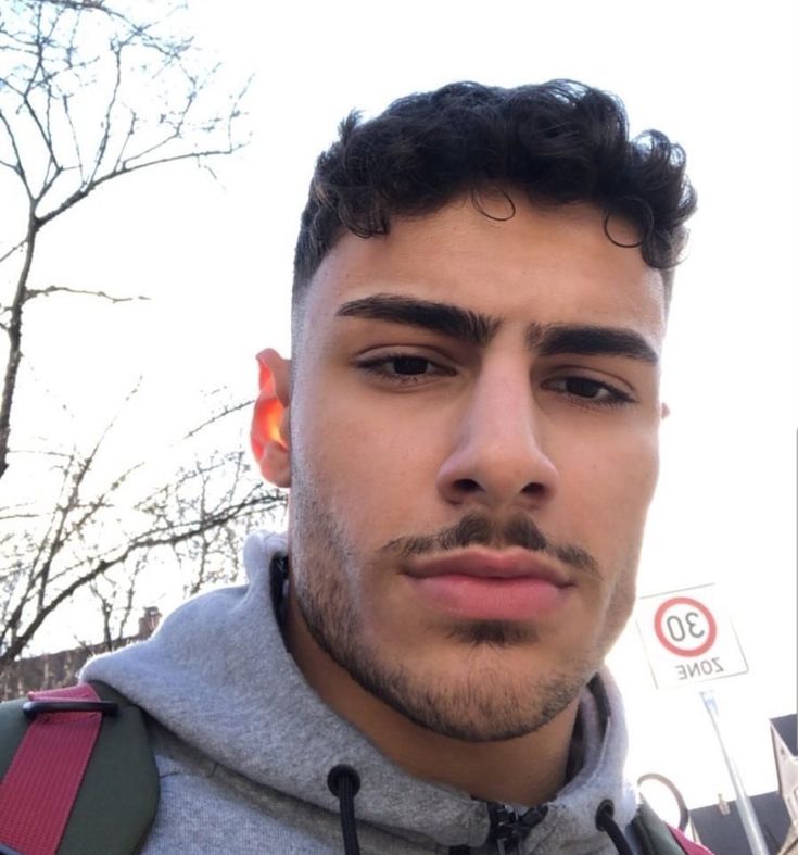 a close up of a person wearing a backpack and looking at the camera with trees in the background