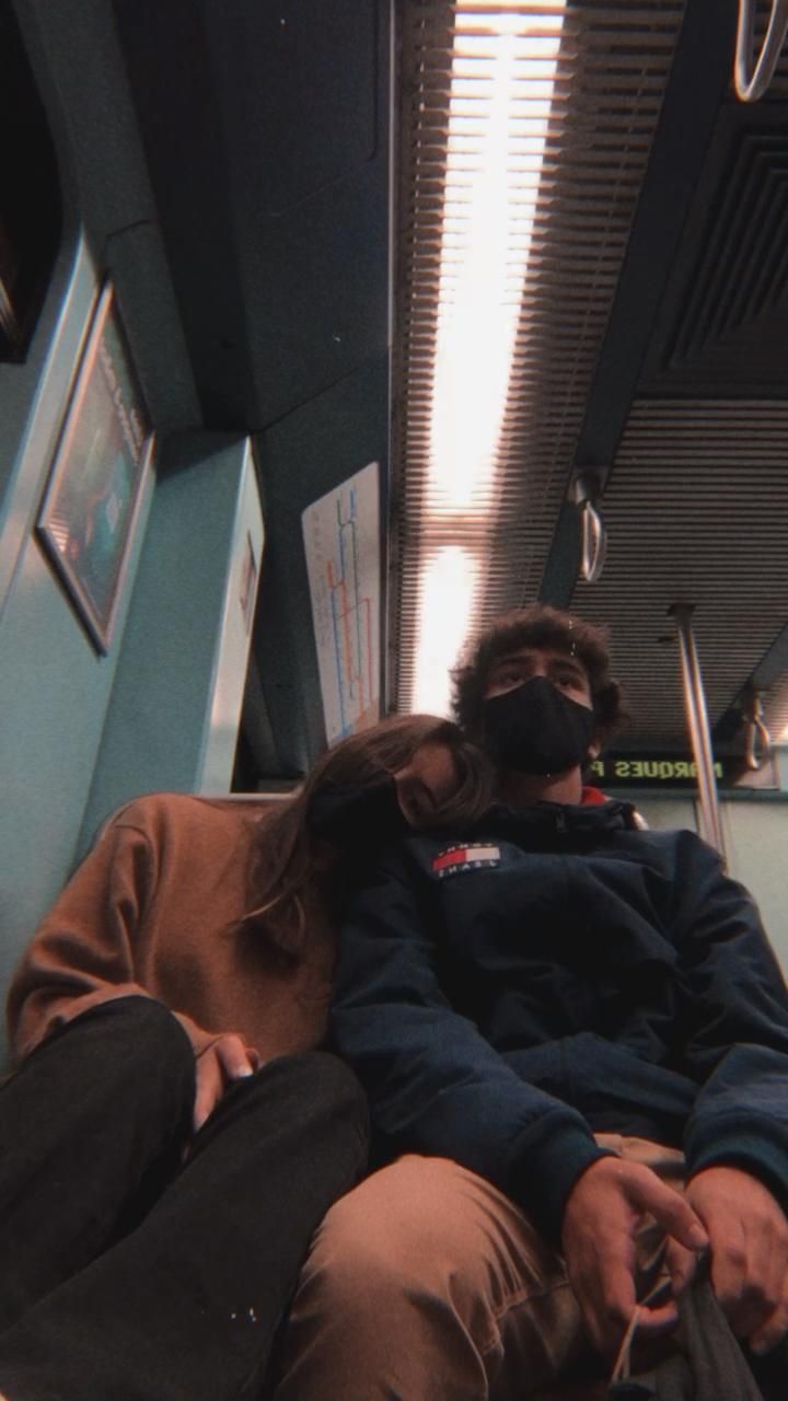 two people sitting on a train with masks on