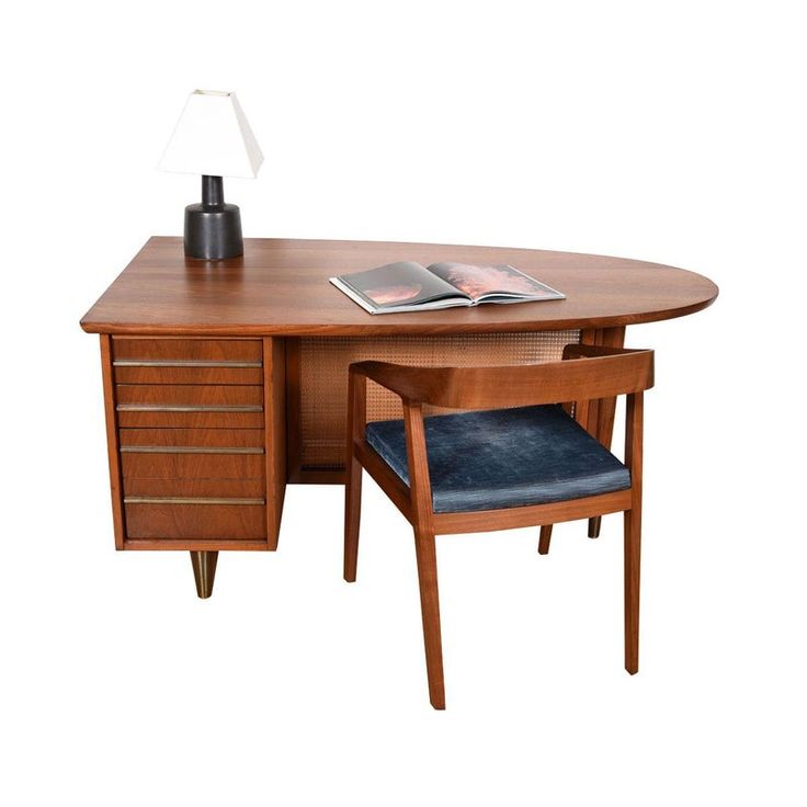 a wooden desk with a lamp on top and a book in front of the desk