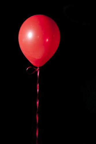 a red balloon floating in the air on a black background