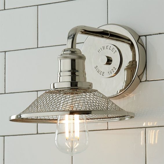 a light that is on the wall next to a white tiled wall with a glass shade