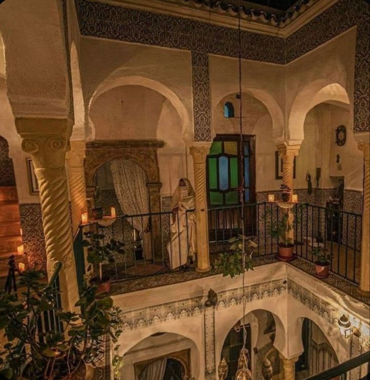 an indoor balcony area with potted plants and candles on the railings at night