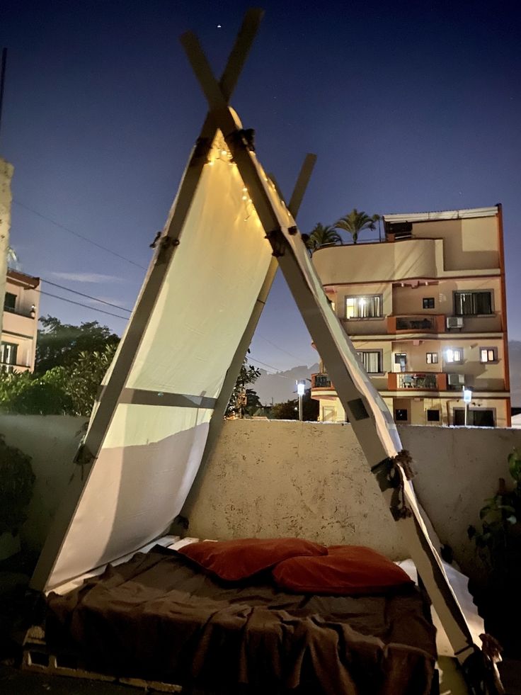 a bed with a tent on top of it in the middle of a city at night