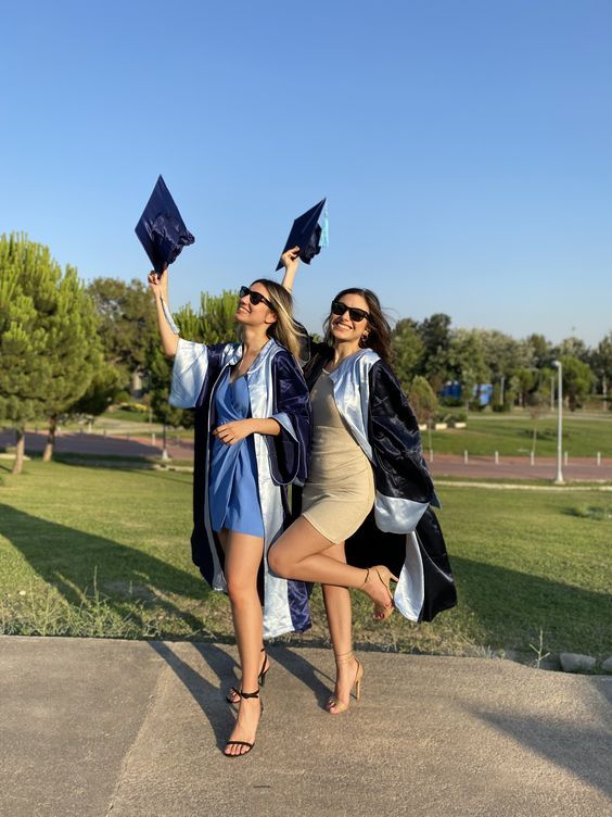 two women in graduation gowns are holding their caps and posing for the camera with one another