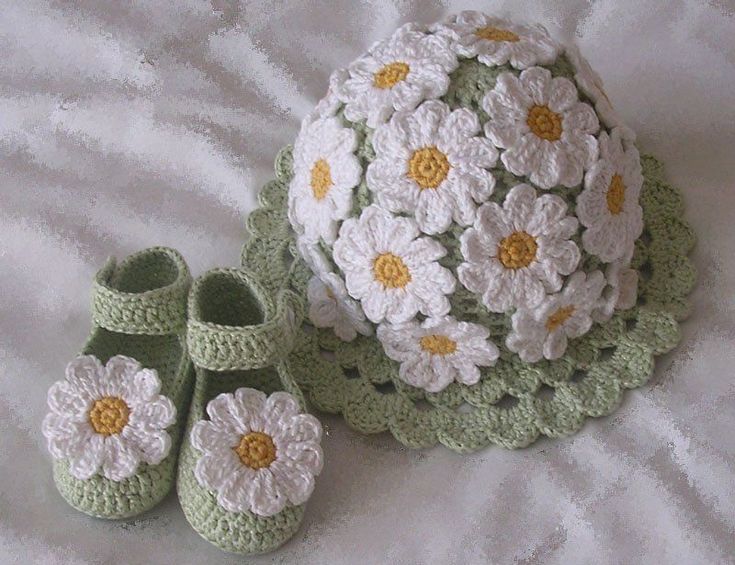 a crocheted hat, booties and blanket on a bed