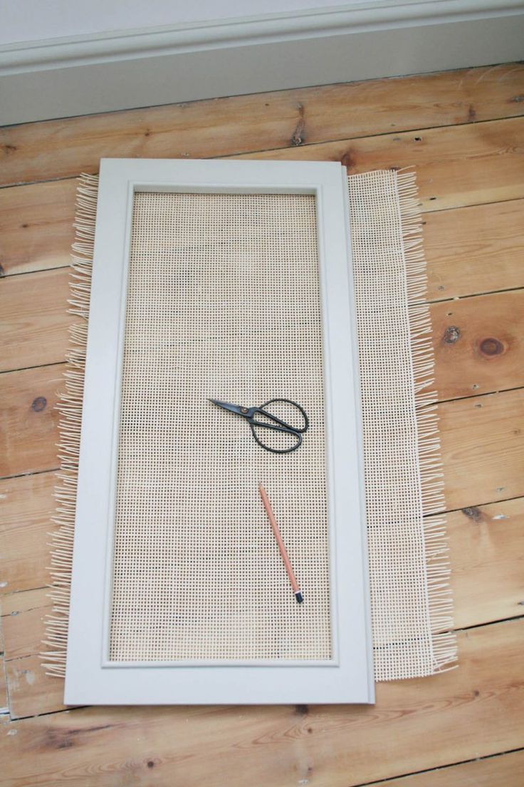 scissors are sitting on the floor in front of a white frame with a string attached to it