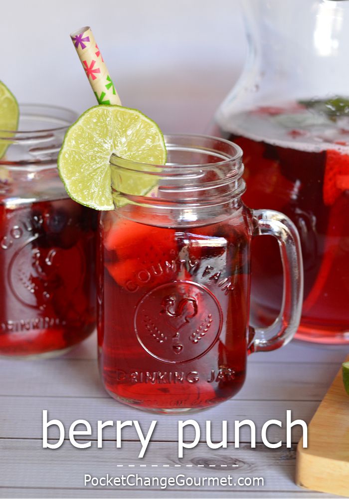 two mason jars filled with red liquid and limes next to a pitcher of water