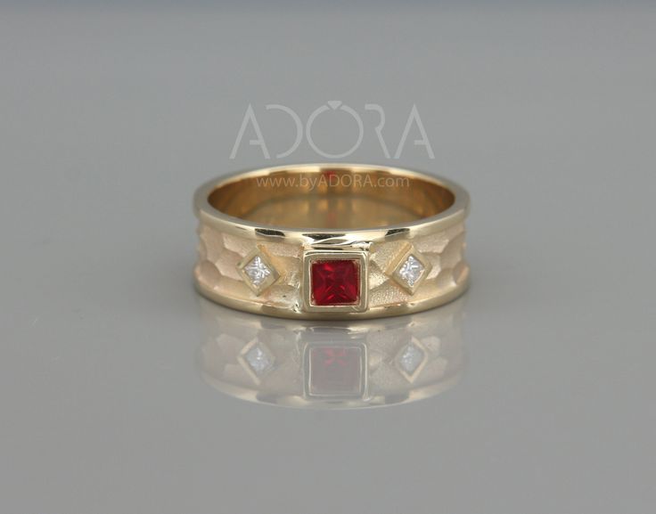 a yellow gold ring with a red stone in the center and diamonds on each side