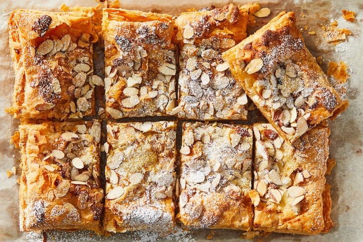 several pieces of dessert sitting on top of a piece of parchment paper covered in powdered sugar