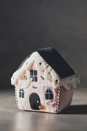 a small doll house sitting on top of a wooden table next to a black and white wall