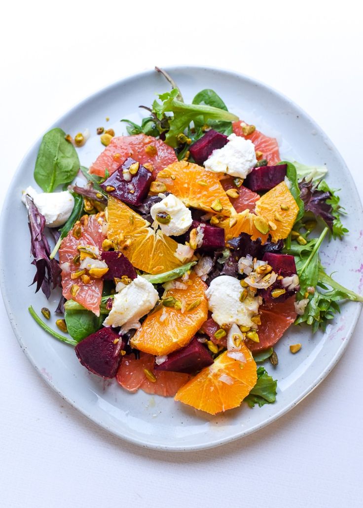 a white plate topped with salad and oranges