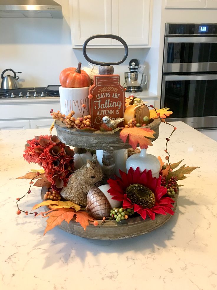 a kitchen counter top with an assortment of fall decorations on it and a candle holder in the center