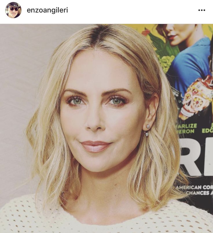 a woman with blonde hair and blue eyes is smiling at the camera while standing in front of a movie poster